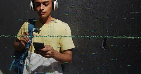Young man wearing headphones using smartphone with glitch overlay against textured wall