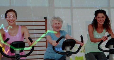 Three women exercising on stationary bikes with performance data