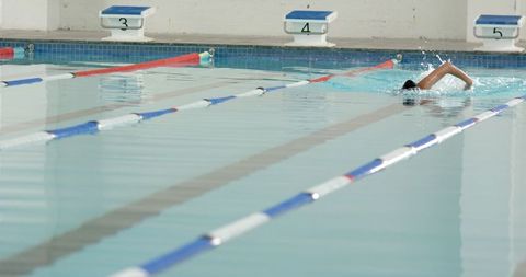 Athlete swimming freestyle in indoor pool lane during practice