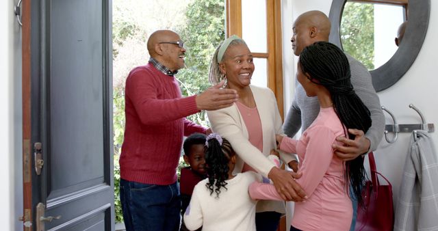 In this welcoming scene, a pair of grandparents embrace their adult children and young grandchildren at the entrance of a home, highlighting family togetherness and love. Useful for themes like family bonding, homecoming, holidays and celebratory gatherings.