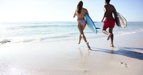 Young Surfing Couple Enjoys Sunny Beach Run