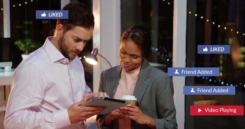 Colleagues reviewing tablet in night office with social media notifications and coffee