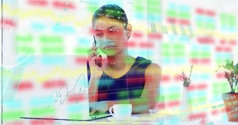 Businesswoman calling while analyzing financial charts on laptop, multitasking in modern workspace