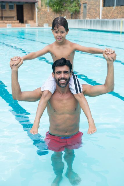 Father carrying son on shoulder in pool at leisure center