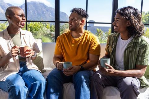 African american friends chatting over coffee on sunlit sofa with mountain view