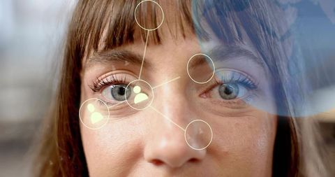 Mid adult woman using augmented reality interface through office glass, close-up eye portrait