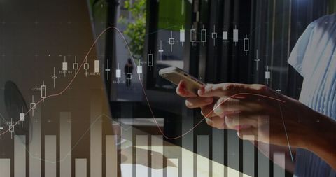 Hands Holding Smartphone Analyzing Financial Data on Laptop