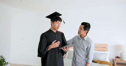Father Congratulating Son in Graduation Gown Receiving Gift