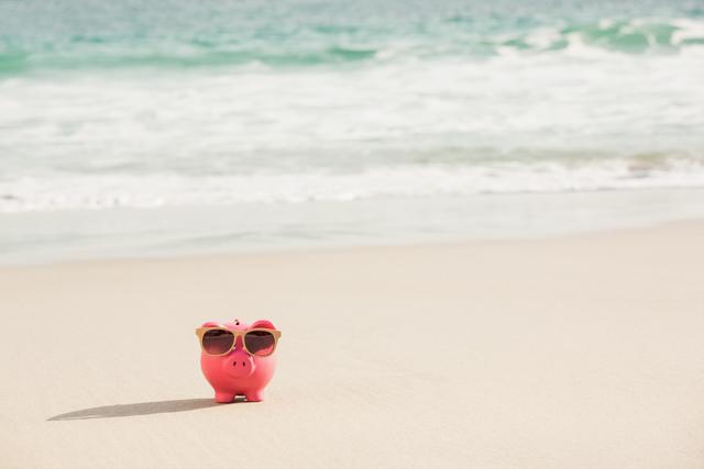 Summer piggy bank with sunglasses on sand - Download Free Stock Photos Pikwizard.com