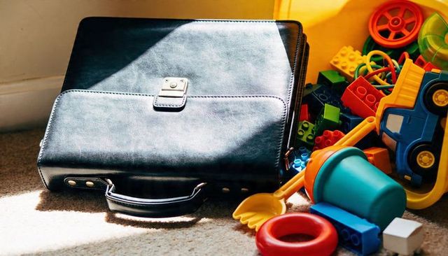 Black leather briefcase lying on carpet among scattered children's toys in sunlight