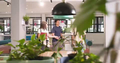 Diverse students walking through campus lounge collaborating with notebooks and devices