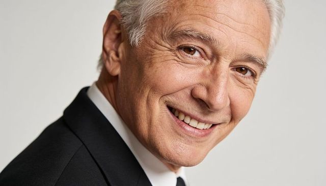 Confident senior executive smiling in formal suit closeup headshot for corporate branding