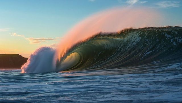Majestic ocean wave barrel at sunrise with rocky coastline