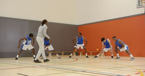 Basketball Team Training Led by Coach at Indoor Gym