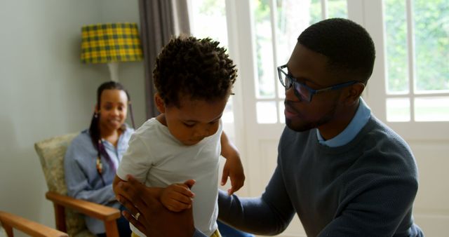 Father Helping Toddler at Home with Mother Watching in Background - Download Free Stock Images Pikwizard.com