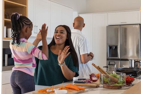 African american family high-fiving on kitchen island while preparing healthy salad