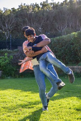 Joyful Father Lifting Son in Sunny Backyard