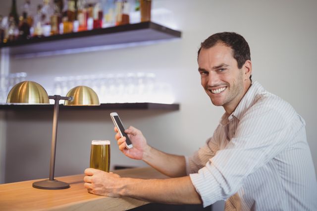 Man using mobile phone while having beer in restaurant