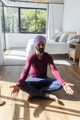 Man Meditating in Sunlit Bedroom Enhancing Tranquility
