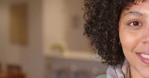 Closeup portrait of smiling woman facing camera with warm kitchen bokeh and copy space