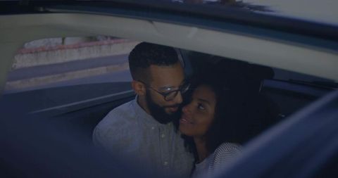 Couple sharing an intimate moment in parked car at dusk