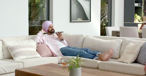 Man Relaxing on Sofa Talking on Smartphone in Living Room