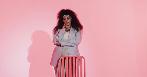 Confident Woman in Blazer Posing Leaning on Pink Chair