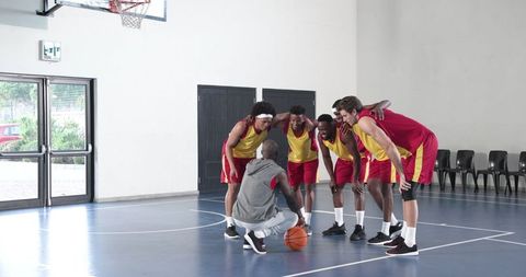 Basketball Coach Motivating Team Players on Indoor Court