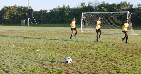 Diverse male soccer players conducting agility drills outdoors