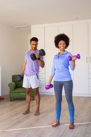 Couple exercising with dumbbells in modern home living room