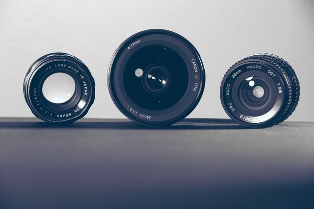 Three camera lenses of different sizes are shown on a grey background. Each lens front element faces the viewer. Ideal for use in photography guides, camera equipment brochures, technology blogs, and visual learning materials for photography enthusiasts.