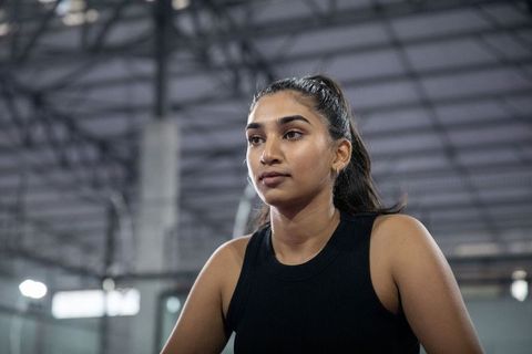 Focused indian female athlete standing in industrial gym interior showing determination