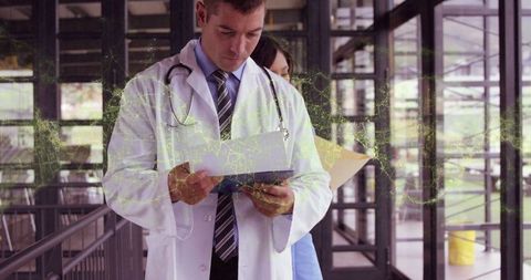 Doctor in Hospital Corridor Reviewing Patient Information