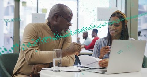 Diverse Coworkers Analyzing Reports on Laptop With Graph Overlays