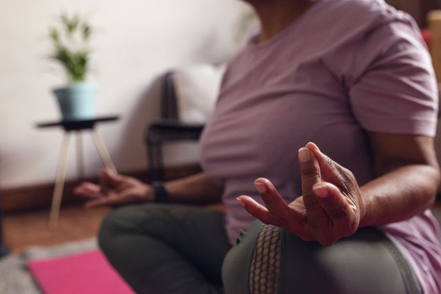 Midsection of a mature woman practicing the seal of sun mudra while meditating at home. This image can be used for promoting mental health, wellness, and self-care practices. Ideal for articles or advertisements related to yoga, meditation, and healthy lifestyles for retirees.