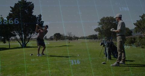 Golfer Swinging on Tee While Partner Observing with Bag and Clubs on Sunny Fairway