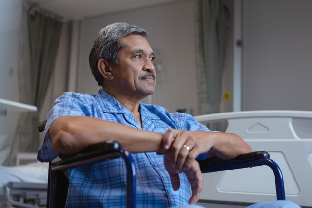 Front view disabled mature male patient sitting on wheelchair and looking away in medical ward at hospital