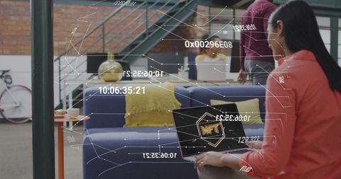 Woman in lounge holding laptop displaying nft graphics