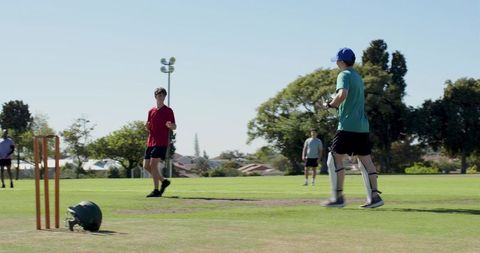 Young cricketer waiting at crease wearing pads and cap on suburban recreational pitch