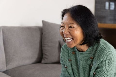 Cheerful Senior Asian Woman Relaxing in Cozy Living Room