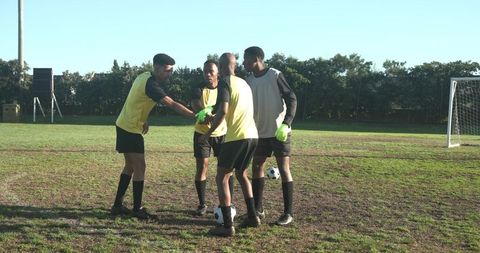 Diverse soccer team huddling for strategy on sunny field