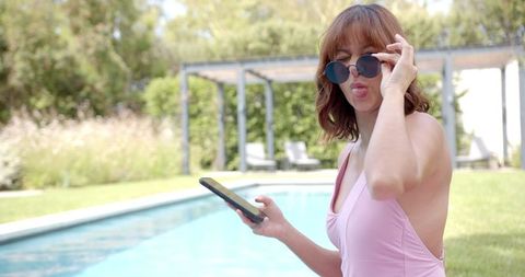 Young Woman Enjoying Sunny Day by Pool in Swimsuit with Phone