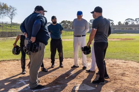 Baseball team holding pregame meeting at home plate with coaches and players
