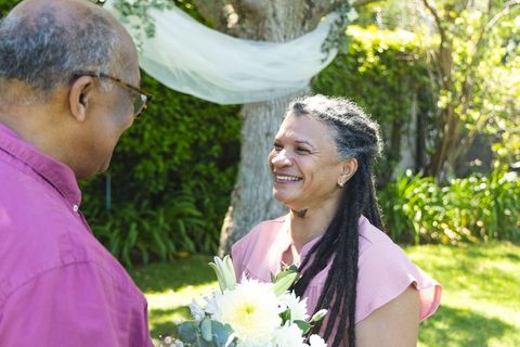African american couple smiling outdoors woman holding bouquet joyful moment in garden