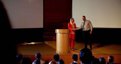 Professionals Shaking Hands During Business Seminar Presentation