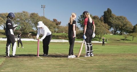 Female Cricket Players Training with Coach on Sunny Day in Park