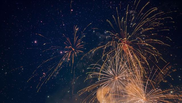 Bursting Golden Fireworks Over Starry Night Sky with Long Trailing Sparks and Smoke