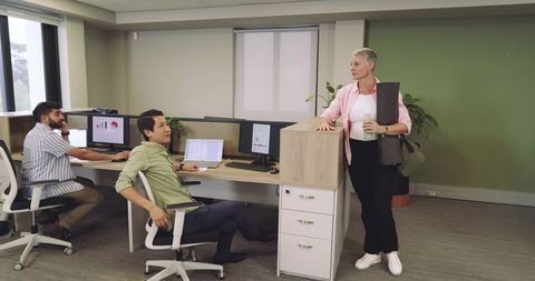 Diverse office team engaging with woman holding yoga mat