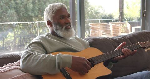 Senior Man Relaxing at Home with Acoustic Guitar