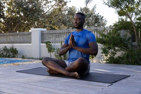 Man Practicing Meditation Outdoors on Deck by Pool